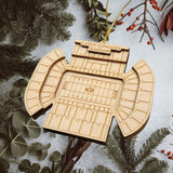 A wooden ornament resembling a football stadium is displayed among pine branches and greenery, with the text "LaVell Edwards Stadium" visible.