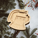 A wooden ornament shaped like a stadium, with the text "Darrell Royal Stadium" visible, is hanging among pine branches and greenery.