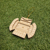 A wooden ornament resembling a football stadium is placed on a grassy surface.