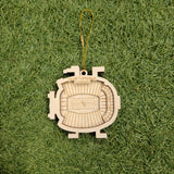 A wooden ornament resembling a football stadium is placed on a grassy surface.