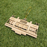 A wooden ornament resembling a stadium or sports arena, with the letters "BYU" visible on it, resting on a grassy surface.